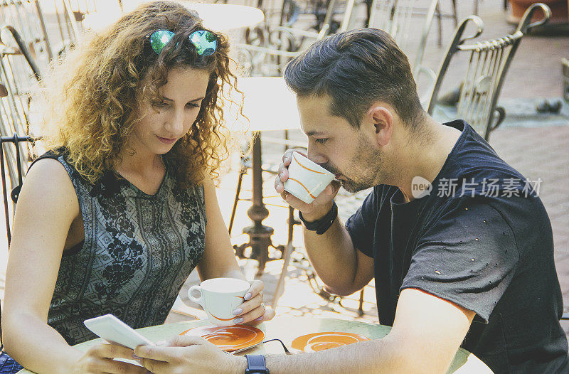 年轻夫妇在咖啡馆喝咖啡，玩平板电脑