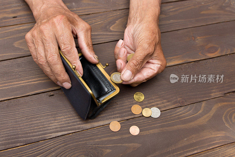 一个老人拿着一个旧硬币钱包和硬币。退休后贫困的概念。