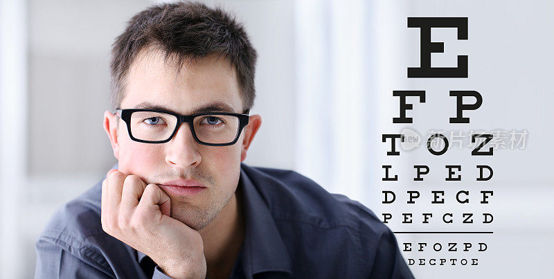 男面戴眼镜视力测试表背景，眼科检查眼科概念