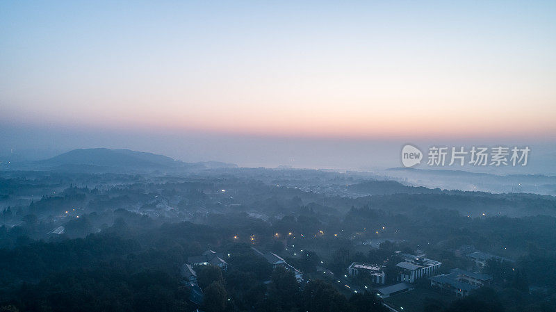 晨曦中，连绵起伏的山丘和村庄被薄雾所覆盖