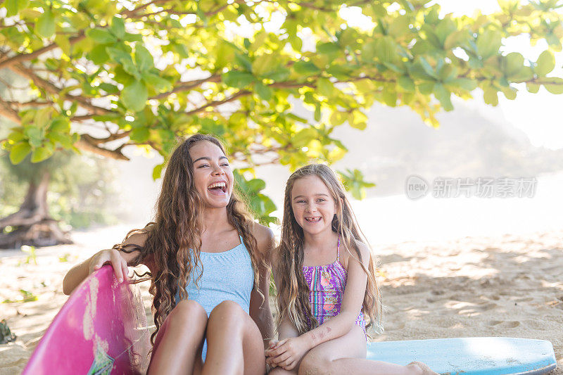 两姐妹在海滩上用冲浪板放松