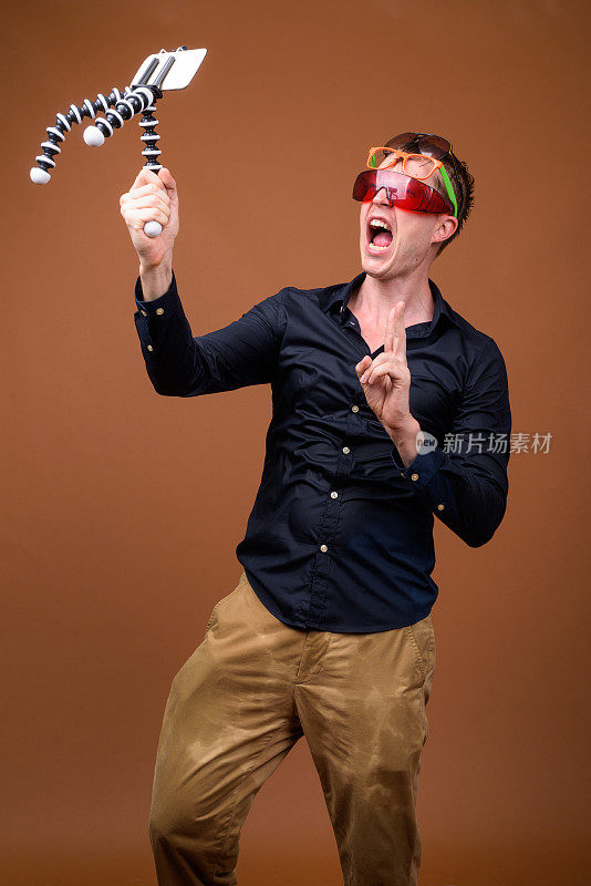 在彩色背景下，一名年轻帅气的男子穿着湿衣服用手机做视频