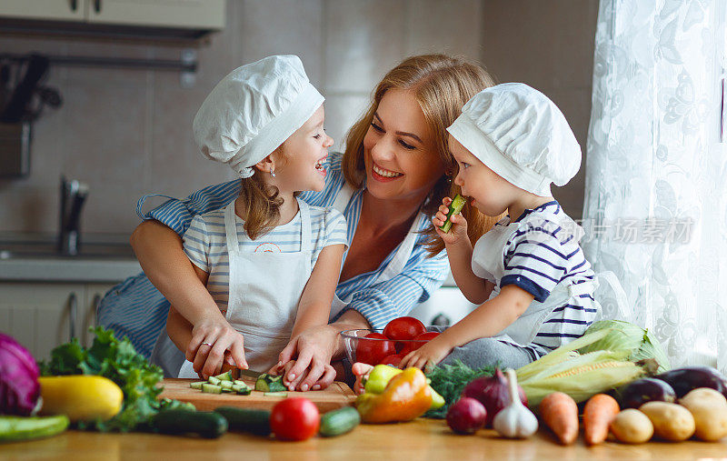 健康饮食。快乐的家庭妈妈和孩子们准备蔬菜沙拉