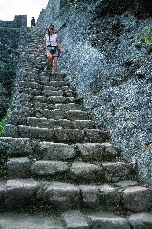 年轻女子下陡峭的马丘比丘台阶，楼梯，墙壁秘鲁遗址
