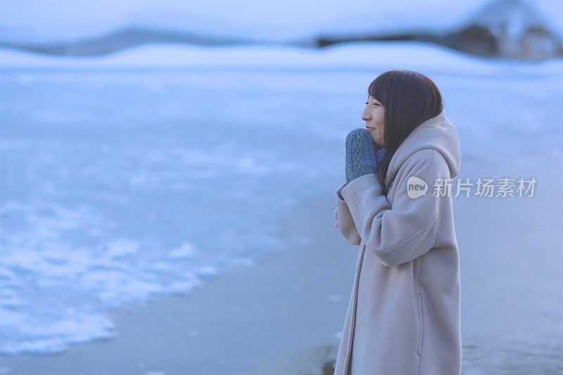 年轻女子站在结冰的池塘边