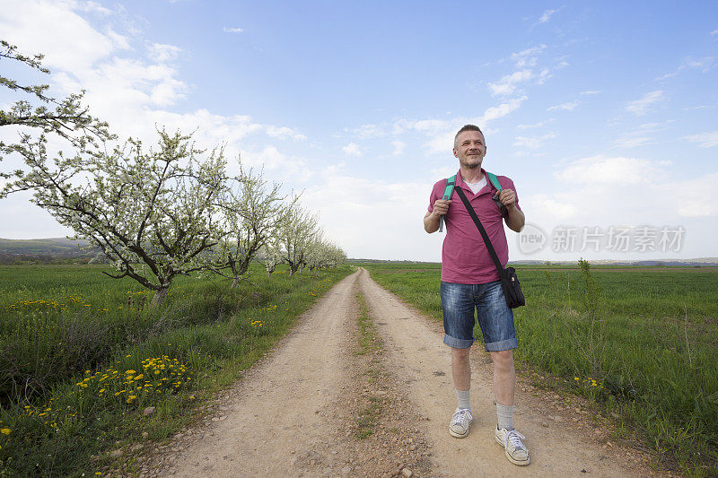 成年男子背着背包在乡村大自然中徒步旅行