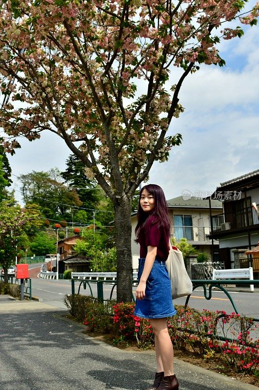 年轻的日本女子站在樱花下