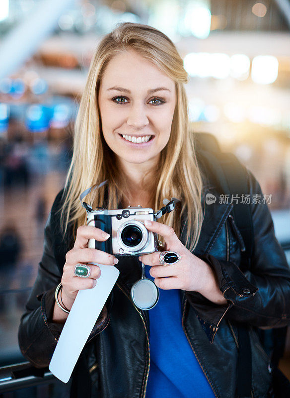在机场拿着照相机和登机牌的年轻女子