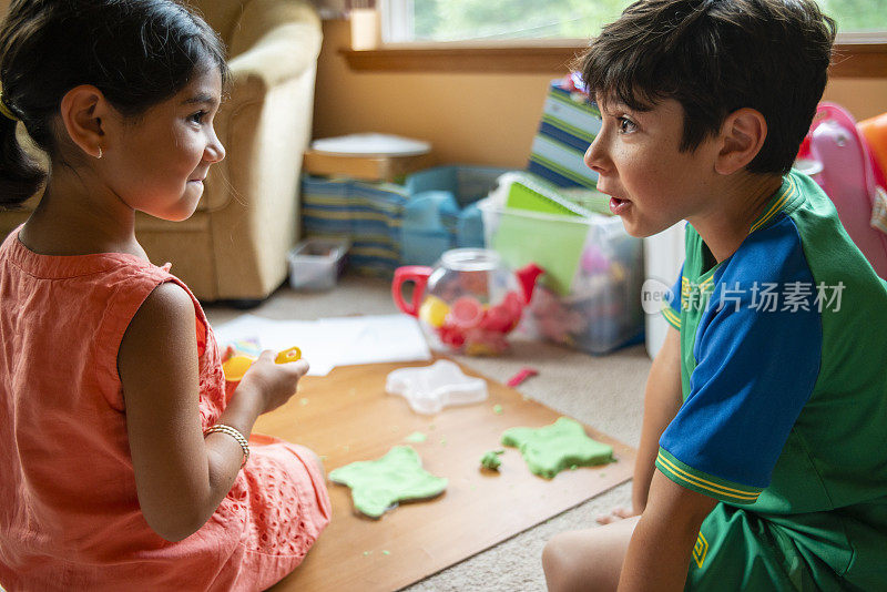 兄弟姐妹。小弟弟和小妹妹，8岁的男孩和6岁的女孩，在儿童房的地板上玩着绿色的玩具沙