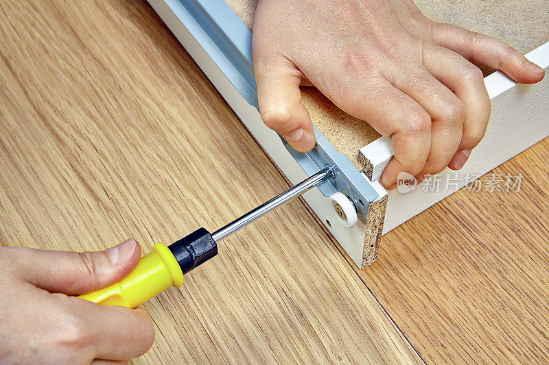 使用家具紧固件和螺丝刀安装抽屉时，特写。