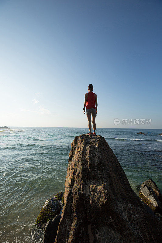 勇敢的女人站在海边的悬崖边