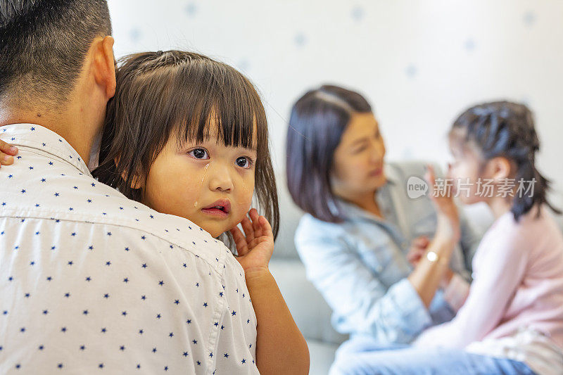 悲伤和哭泣的亚洲女孩被他们的父母安慰