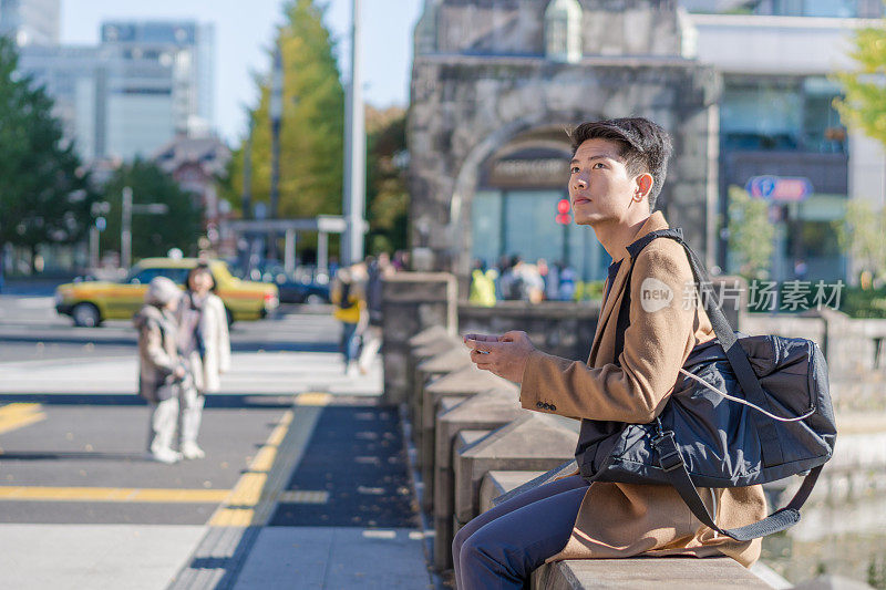 年轻的亚洲男子和日本朋友寻找旅游地点使用手机和花时间在亚洲旅行