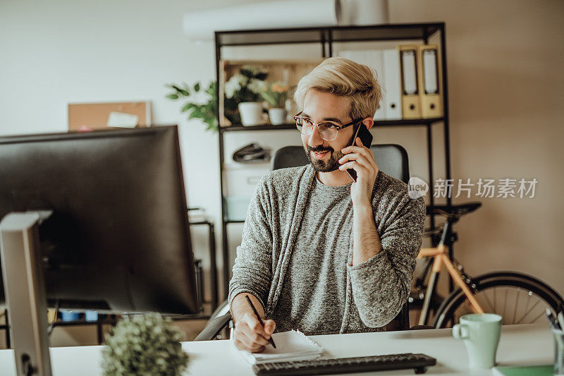 年轻的潮人早上在办公室用智能手机聊天