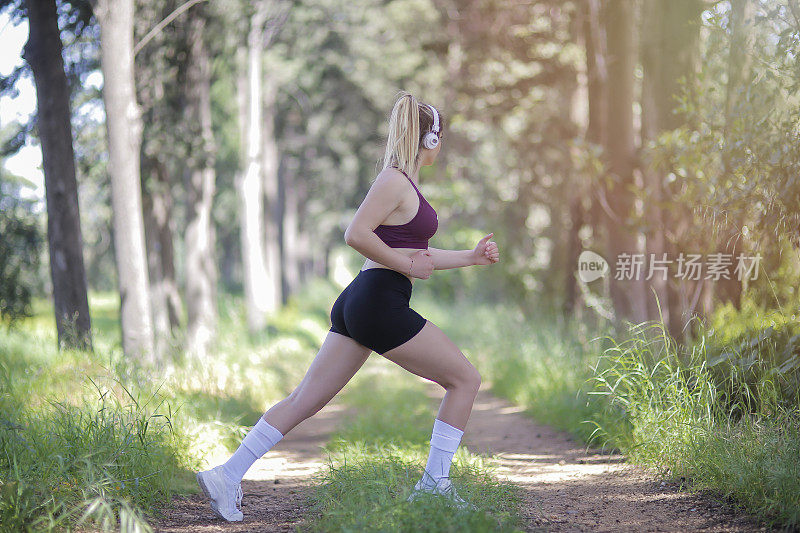 年轻的女运动员在森林里慢跑。晨跑者做体能训练。