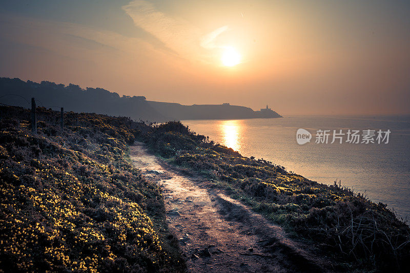 日出在一个夏天沿着悬崖小径散步，崎岖的海岸线和平静的水