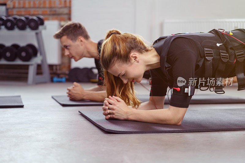 在健身房，除了男人，女人也在瑜伽垫上锻炼
