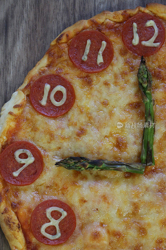 这是一个自制披萨时钟的图片，上面有意大利辣香肠片、马苏里拉奶酪和芦笋作为时钟指针，显示时间21:00