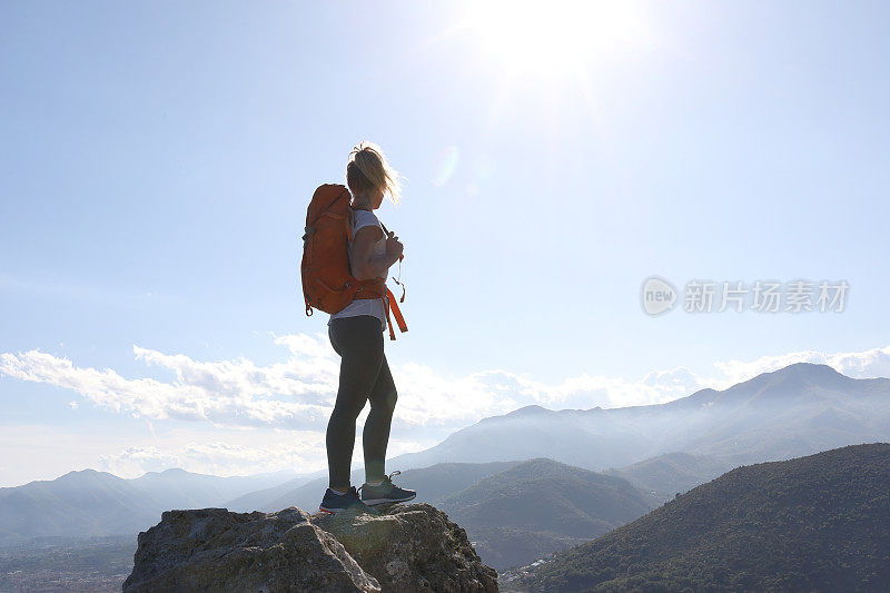 年轻女子背着双肩包在山上的岩石上