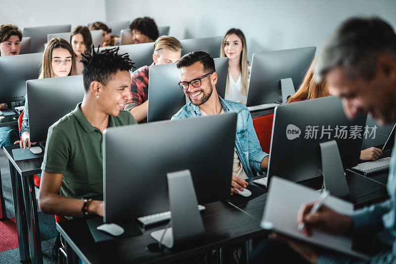 快乐的学生在计算机实验室的课堂上交流。