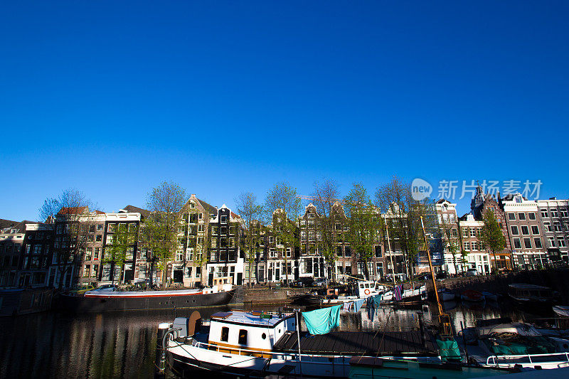 荷兰阿姆斯特丹:阳光照耀的黎明运河船屋晾着衣服