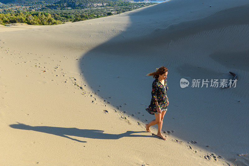 一个年轻漂亮的女人走在沙丘上。