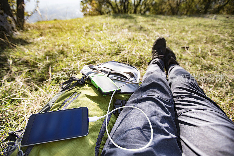 用太阳能电池给手机充电的徒步旅行者