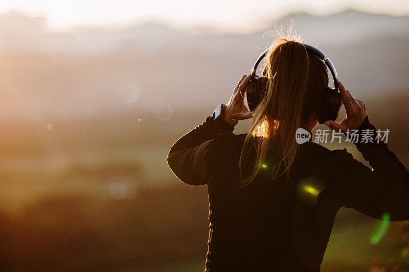 女孩戴着耳机在夕阳下听音乐