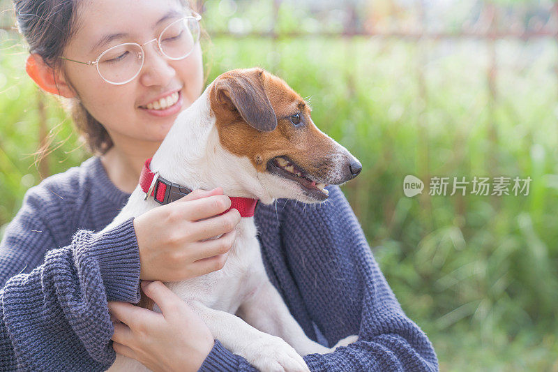 亚洲女孩与他们的宠物狗放松和花时间一起在公园户外