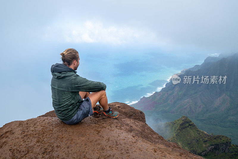 一名男子在夏威夷徒步旅行，从山顶眺望风景