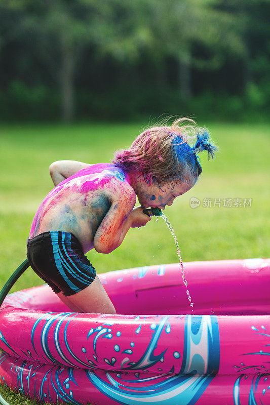 弟弟和妹妹在后院玩彩色粉末，在孩子的游泳池里洗澡