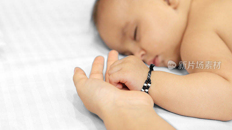 婴儿抱着妈妈的手睡觉