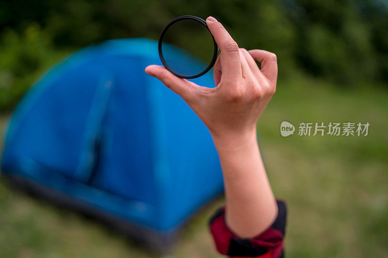 女孩手握暖，中性密度或偏光高质量的玻璃滤镜，把她的相机镜头