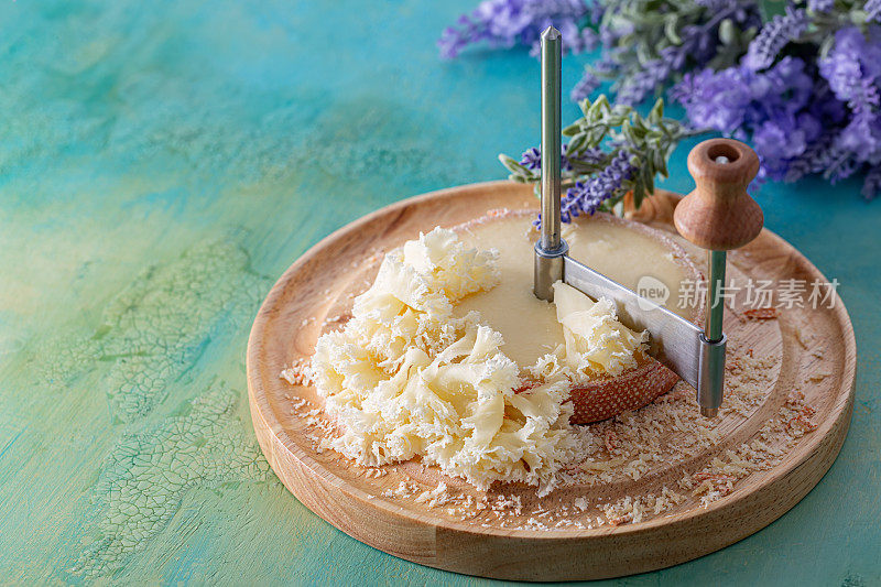 法国奶酪和尚头与丁香花瓣切成薄片，放在木制的圆形表面上。束薰衣草。