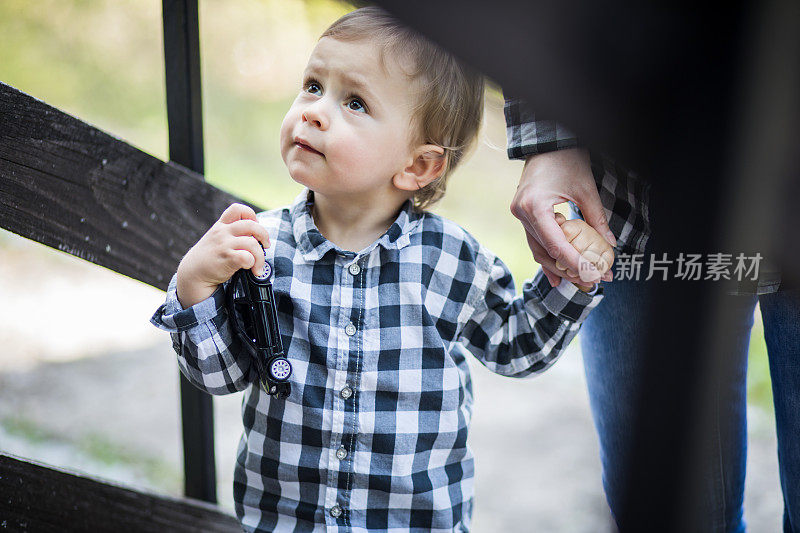 漂亮的蹒跚学步的小男孩和妈妈一起走，楼梯在户外