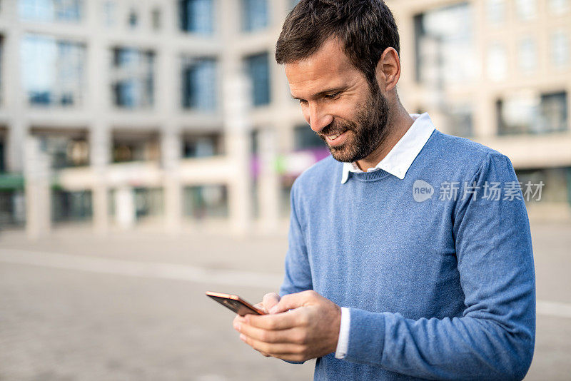 快乐的中年男人在城市街道上发短信。