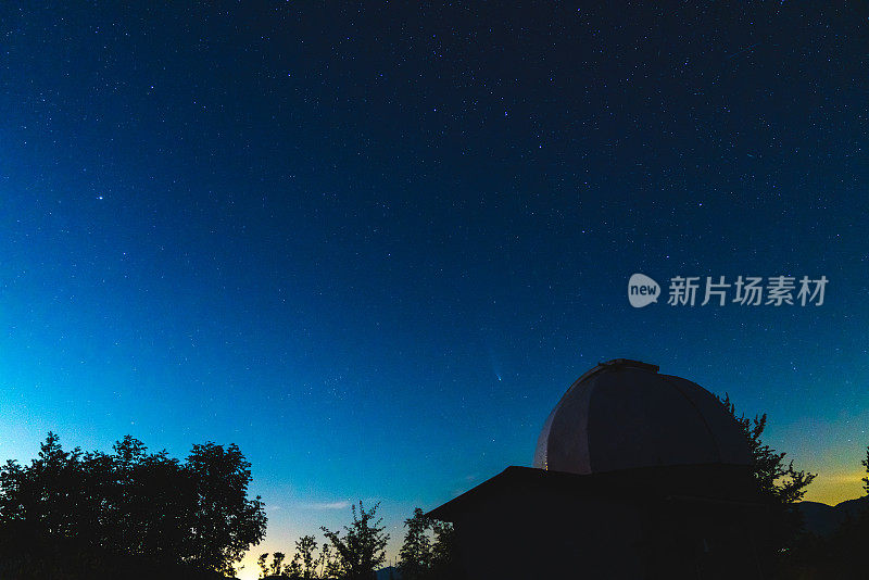 一个夜晚有星星和Neowise彗星在背景的天文台