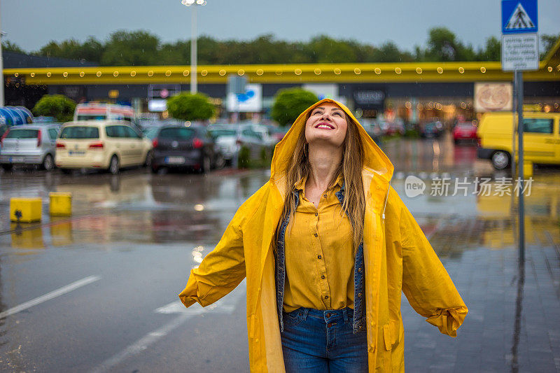 穿着雨衣的年轻女子正在享受雨