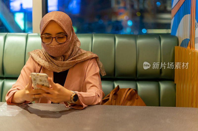 亚洲千禧一代商业女性坐在餐厅，有社交距离标志