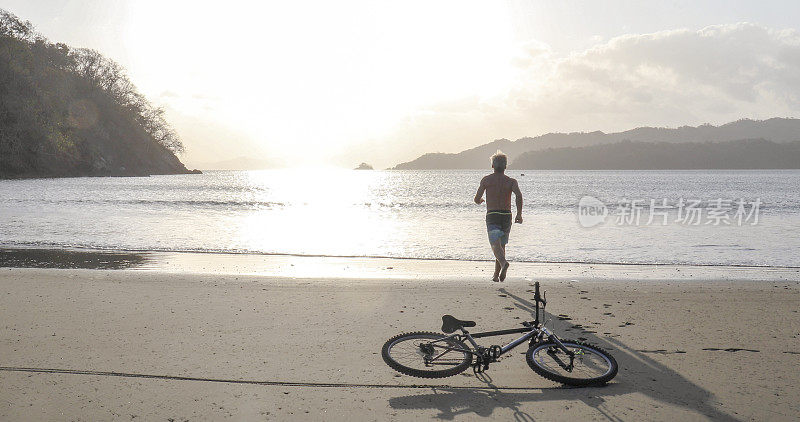 骑山地车的人在日出时跑下沙滩