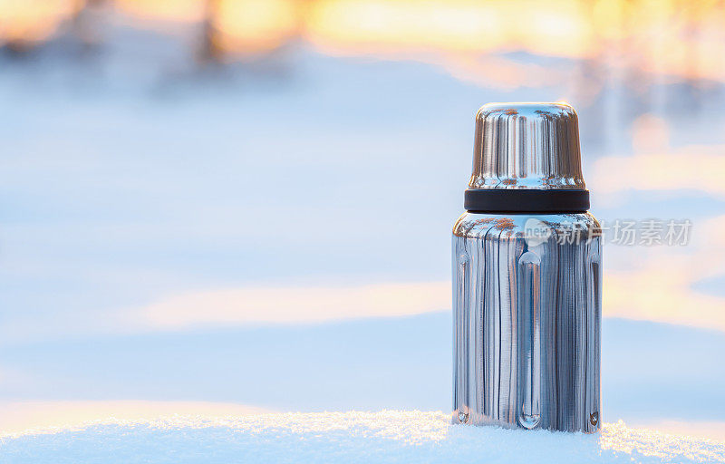 清晨白雪上的热水瓶。冬季徒步和休闲的概念。