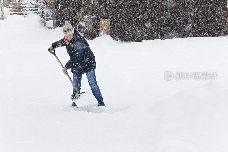 妇女在屋前铲雪