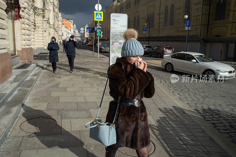 在莫斯科市中心一个阳光明媚的日子里，一位妇女用手帕擤鼻子。