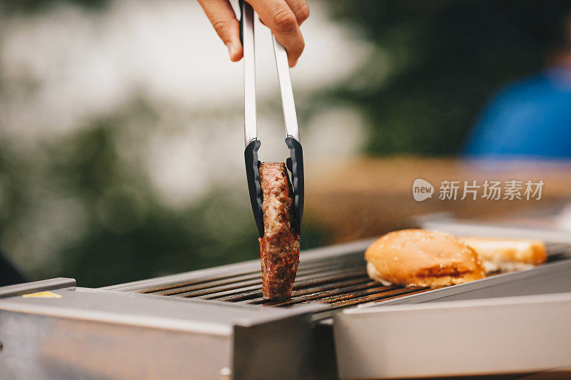 厨师在烤架上烹饪汉堡肉饼。