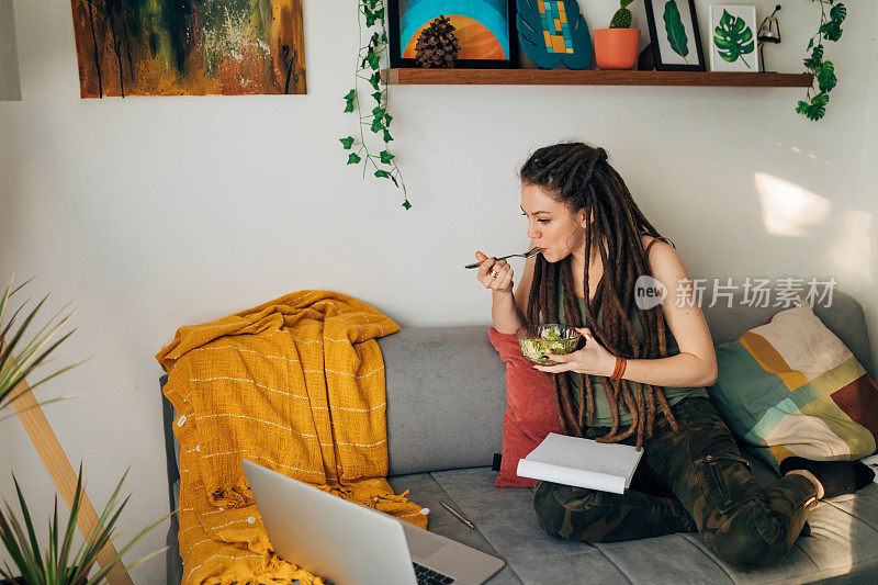 在她繁忙的在线课程安排中，专注的女学生一边听课一边吃饭