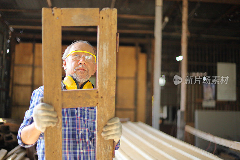 年长的亚洲木匠正在他自己的车库风格的车间修理木框架在退休年龄的爱好