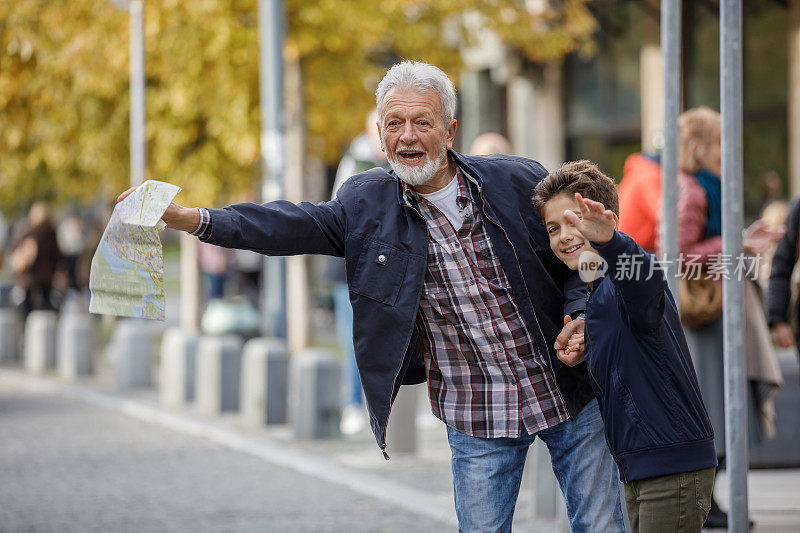 一个年长的男人和小男孩的肖像谁是站在城市的街道和试图赶上一程。