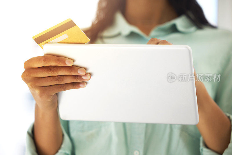 一个不知名的人用信用卡和平板电脑在家网上购物的剪影