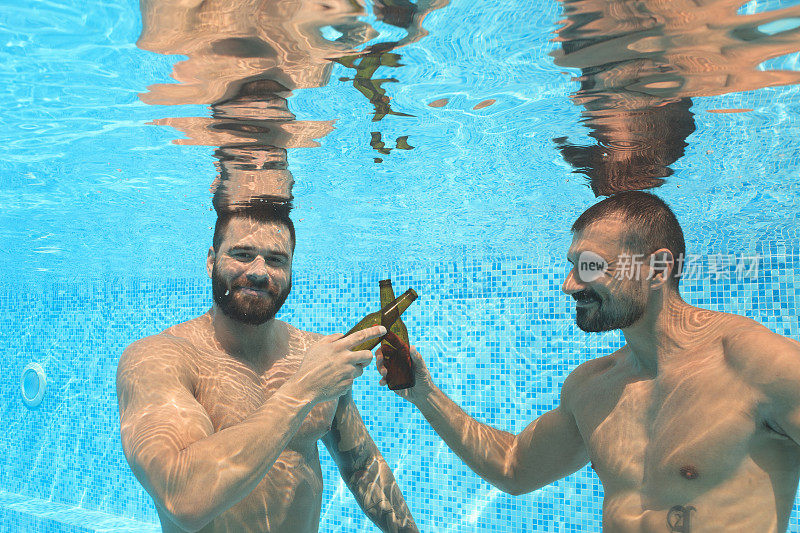 朋友们两个肌肉男在游泳池里喝啤酒