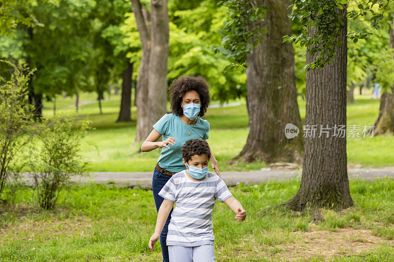 非裔美国母亲在城市公园里与她可爱的小男孩度过一段时间。